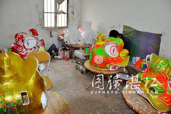 生龙活虎的醒狮。 碧海银沙网讯(图文/黎 明 编辑/小 飞 云 海)1月11日,冬日的湛江有些许寒冷,遂溪县黄略镇龙湾村国家级非物质文化遗产项目遂溪醒狮代表性传承人李荣仔的龙狮作坊热火朝天,32名工人正在加班加点赶制全国各地春节期间需要的五彩龙、醒狮和锣鼓,他们为上海世博会博物馆赶制的四头大醒狮终于完工发货。 李荣仔和他制作的大醒狮。 绘制图案。 曾为国庆六十周年庆典、上海世博会开幕式庆典和广州亚运会龙舟赛制作龙狮、赛鼓的李荣仔介绍,刚刚为上海世博博物馆发去的四只醒狮有5.